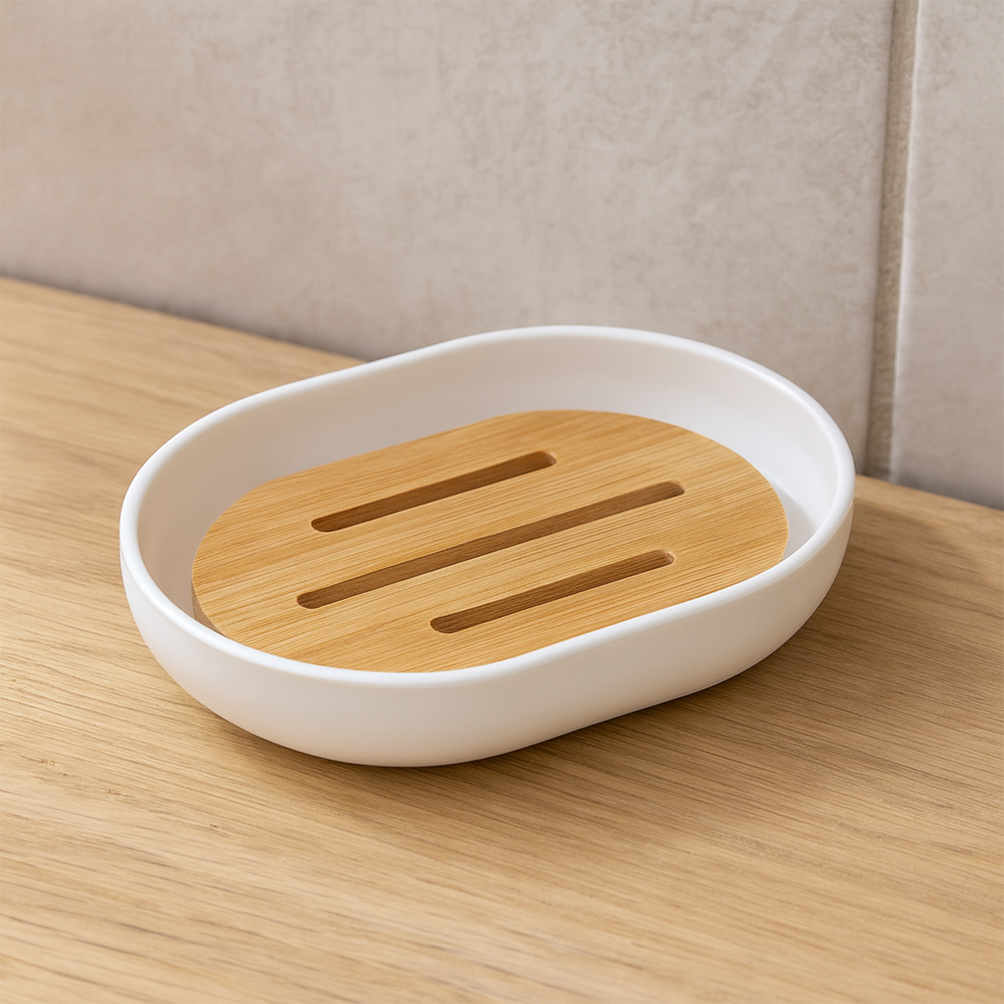 Empty white soap dish with slotted bamboo insert on wooden surface