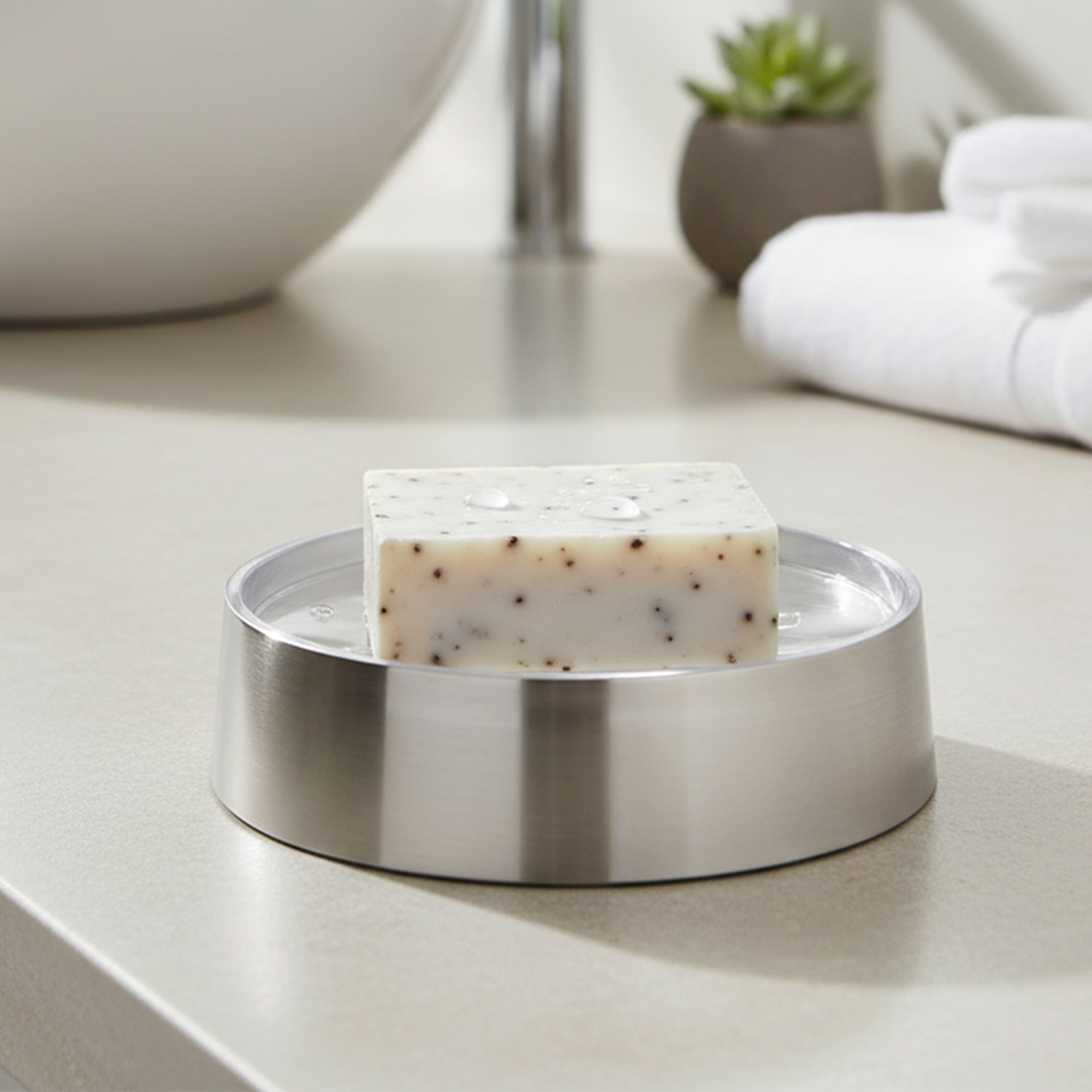 Bar soap resting on brushed aluminum soap dish on vanity