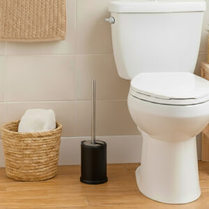 Matte black toilet brush with stainless steel handle beside white toilet in bathroom with woven basket on wood floor