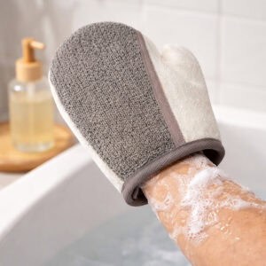 Person wearing gray and white exfoliating glove on soapy hand