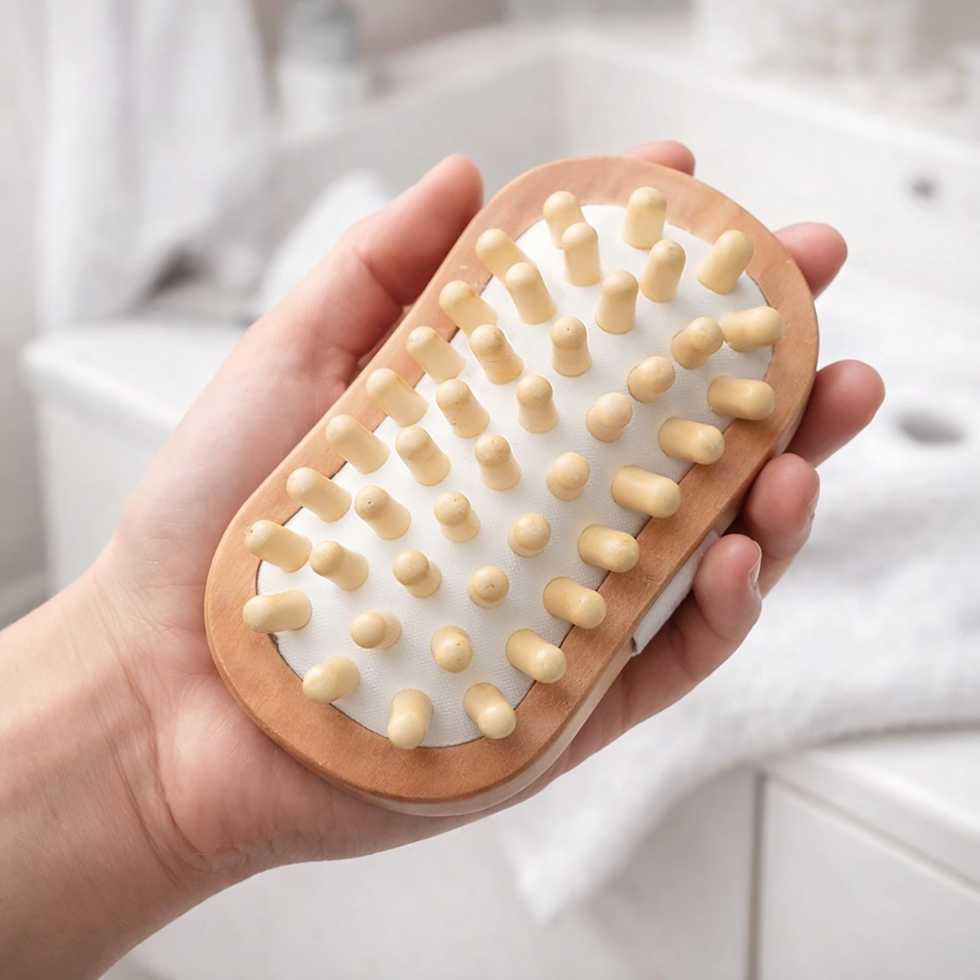 Hand holding wooden massage brush with rounded nubs