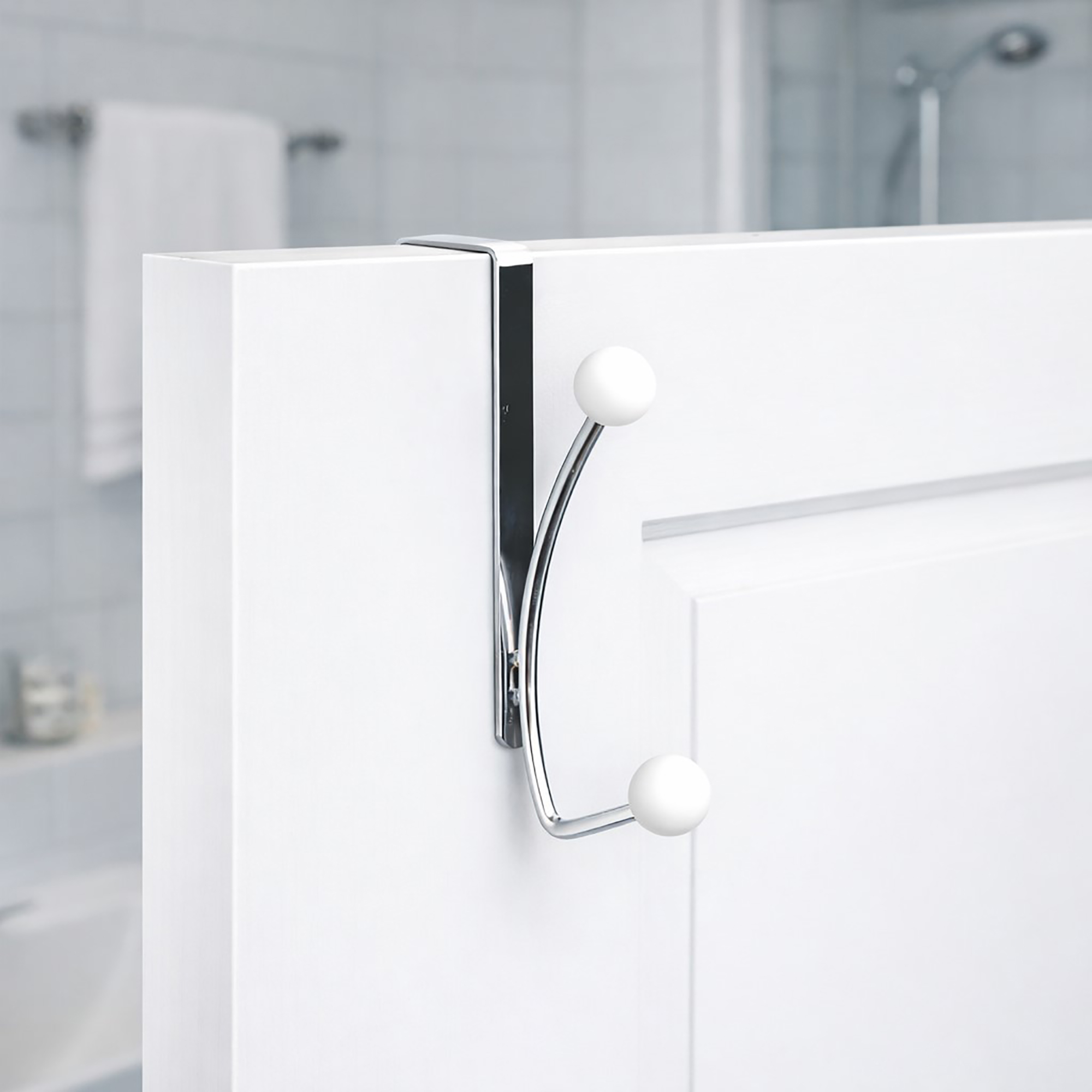 "Chrome double hook with white ball ends mounted on white bathroom door"