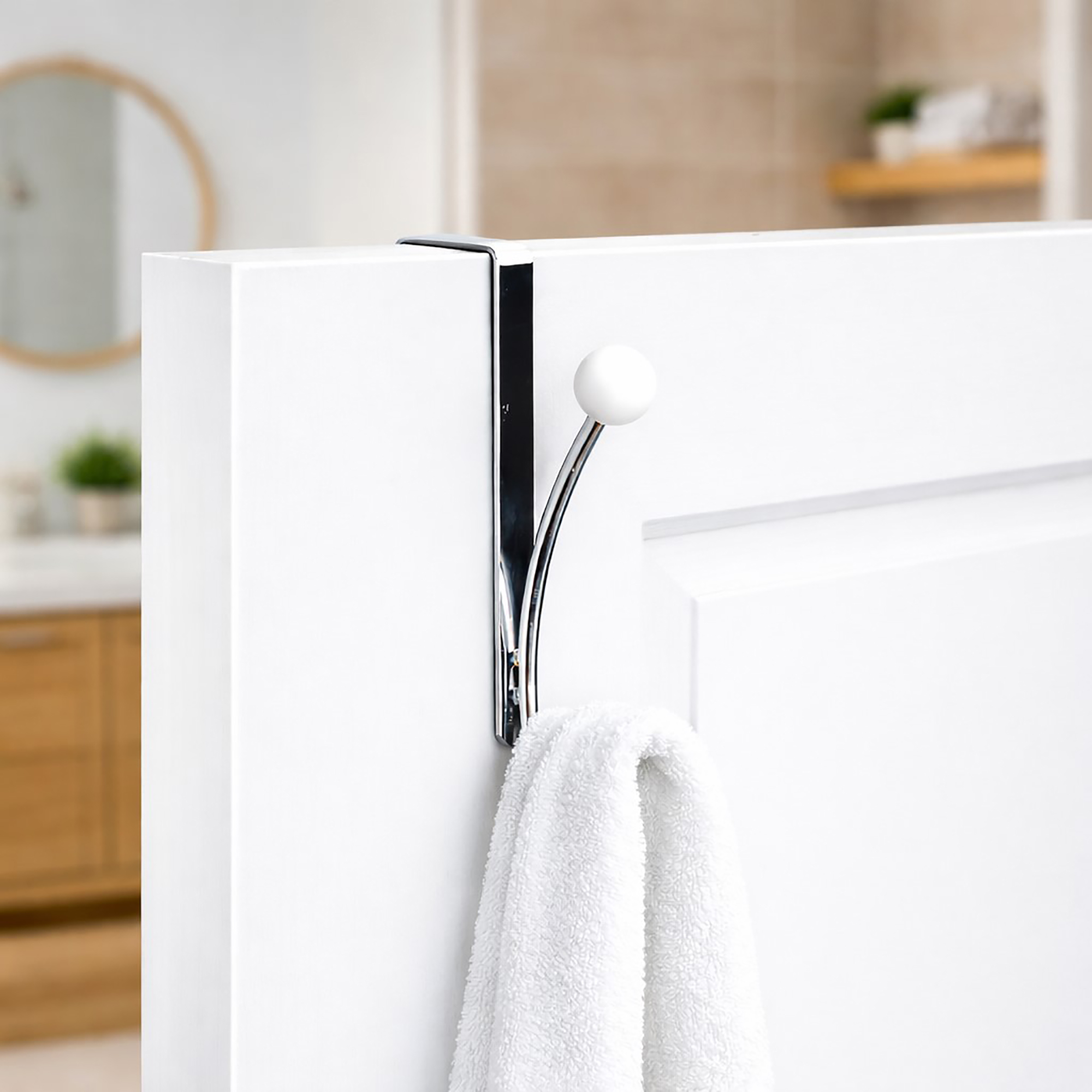 "Chrome over-the-door hook holding white towel on white door"