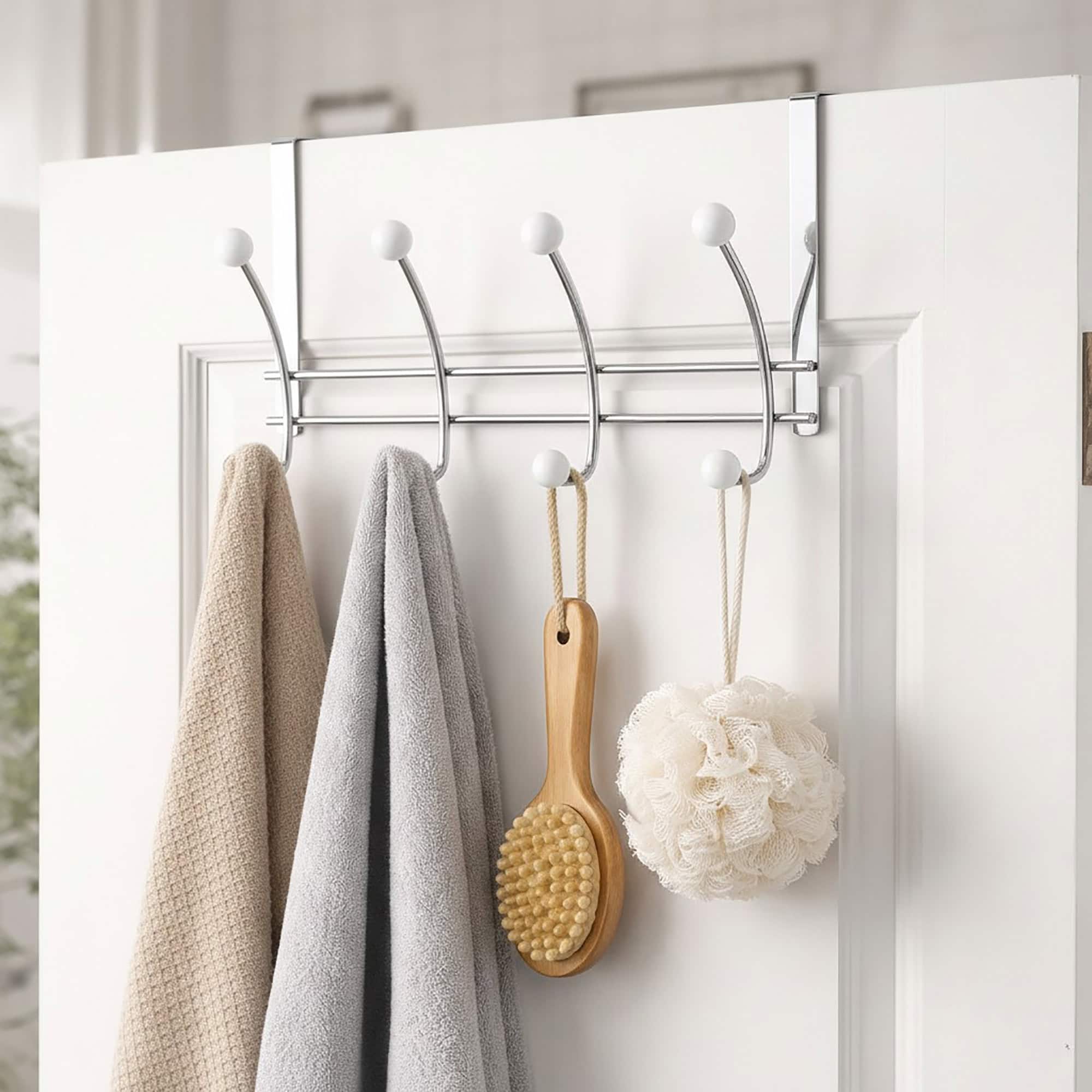 "Chrome over-the-door hook rack holding towels, bath brush, and loofah on white bathroom door"