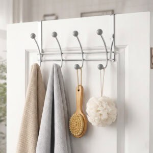 "Chrome over-the-door hook rack with gray ball ends holding towels, bath brush, and loofah on white door"