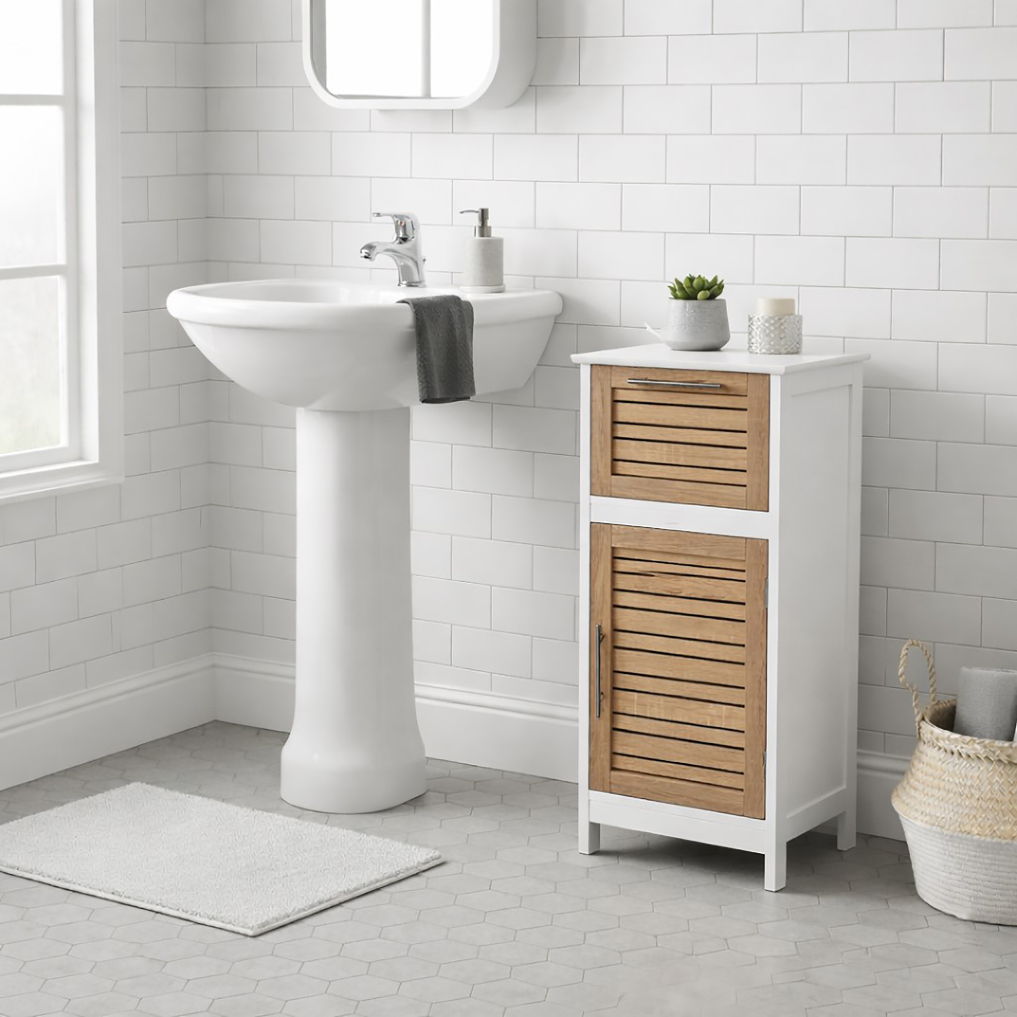 "Compact bathroom cabinet with vented oak doors beside a pedestal sink in a white tiled bathroom"