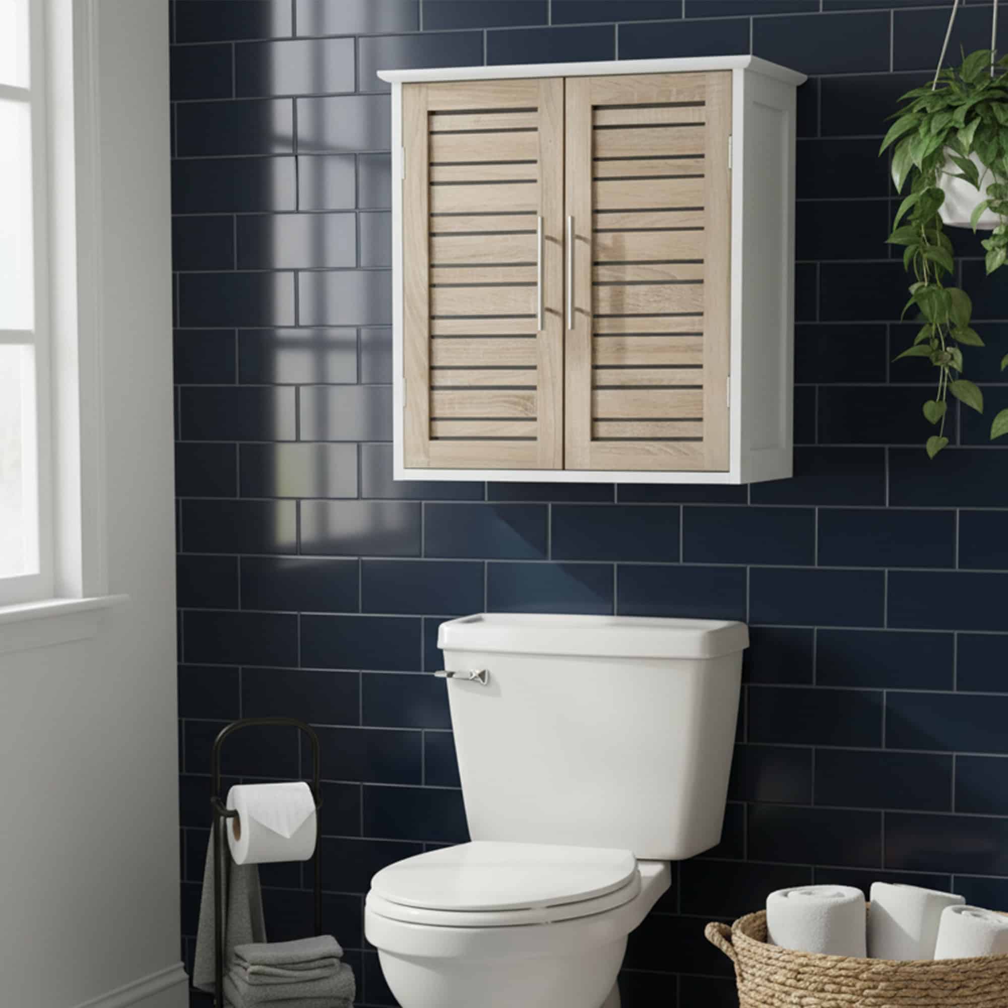 "White and oak louvered wall cabinet with stainless steel handles mounted above a toilet against dark blue subway tiles"