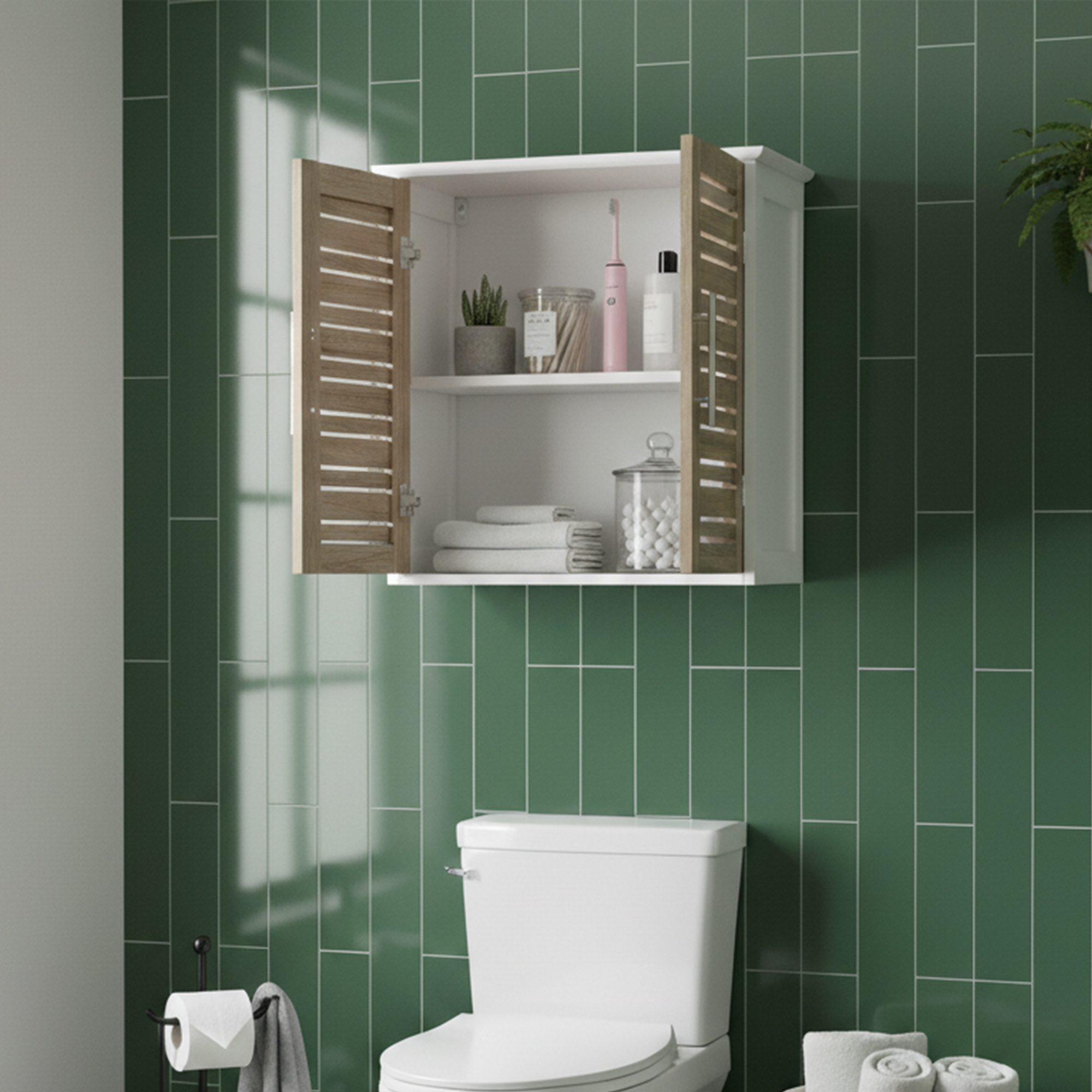 "Open double-door oak and white wall cabinet with two shelves holding toiletries and towels, mounted above a toilet on green tiled wall"