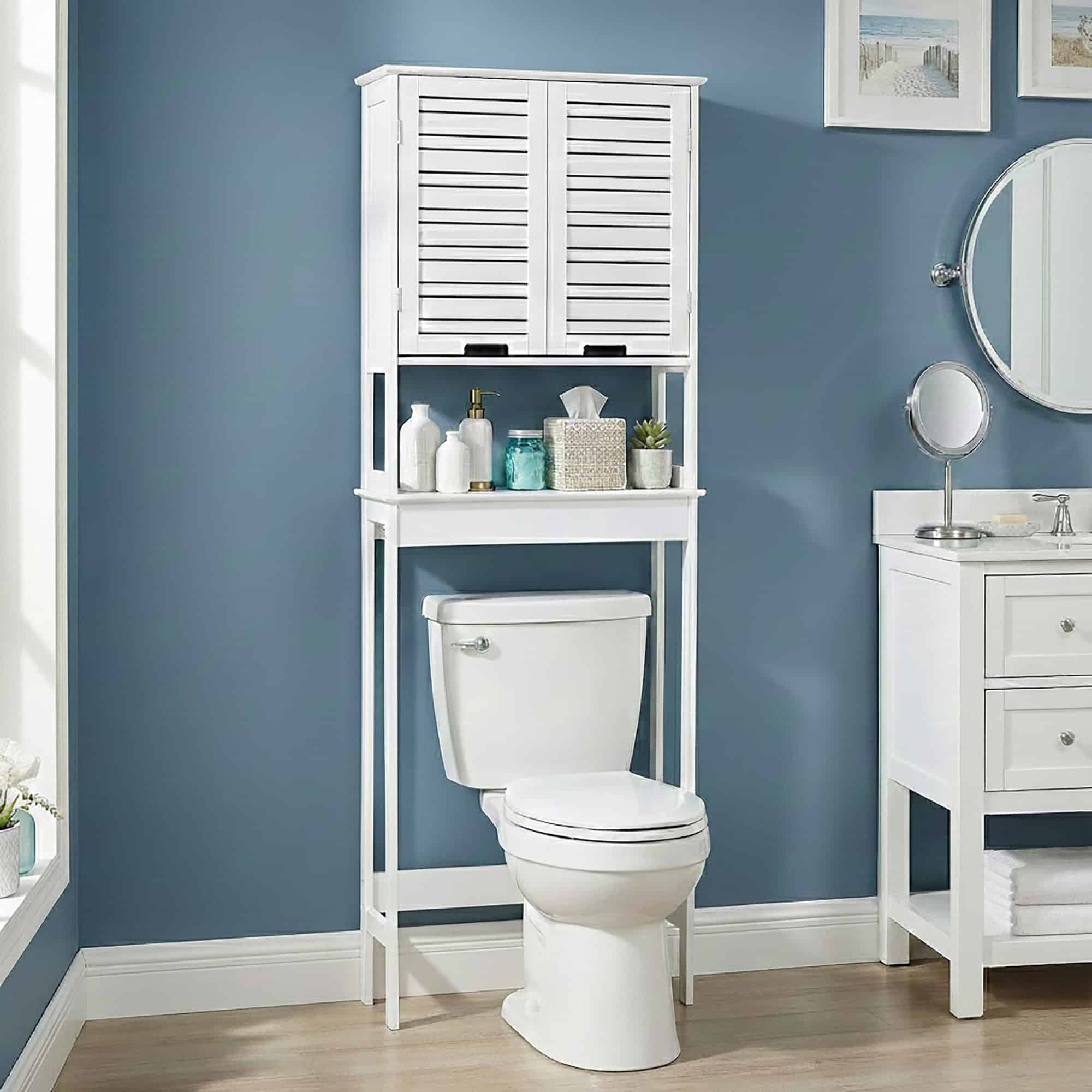 “White over-the-toilet storage unit with slatted doors styled in blue bathroom”