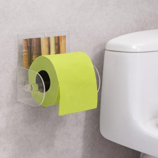 Bamboo clear acrylic toilet paper holder suction-mounted on grey wall beside a toilet, holding a lime-green roll. Graphic insert shows a bamboo-stalk photo.