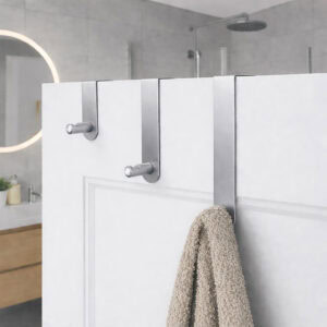 "Three brushed steel over-door hooks on white paneled bathroom door with beige towel on lowest hook"