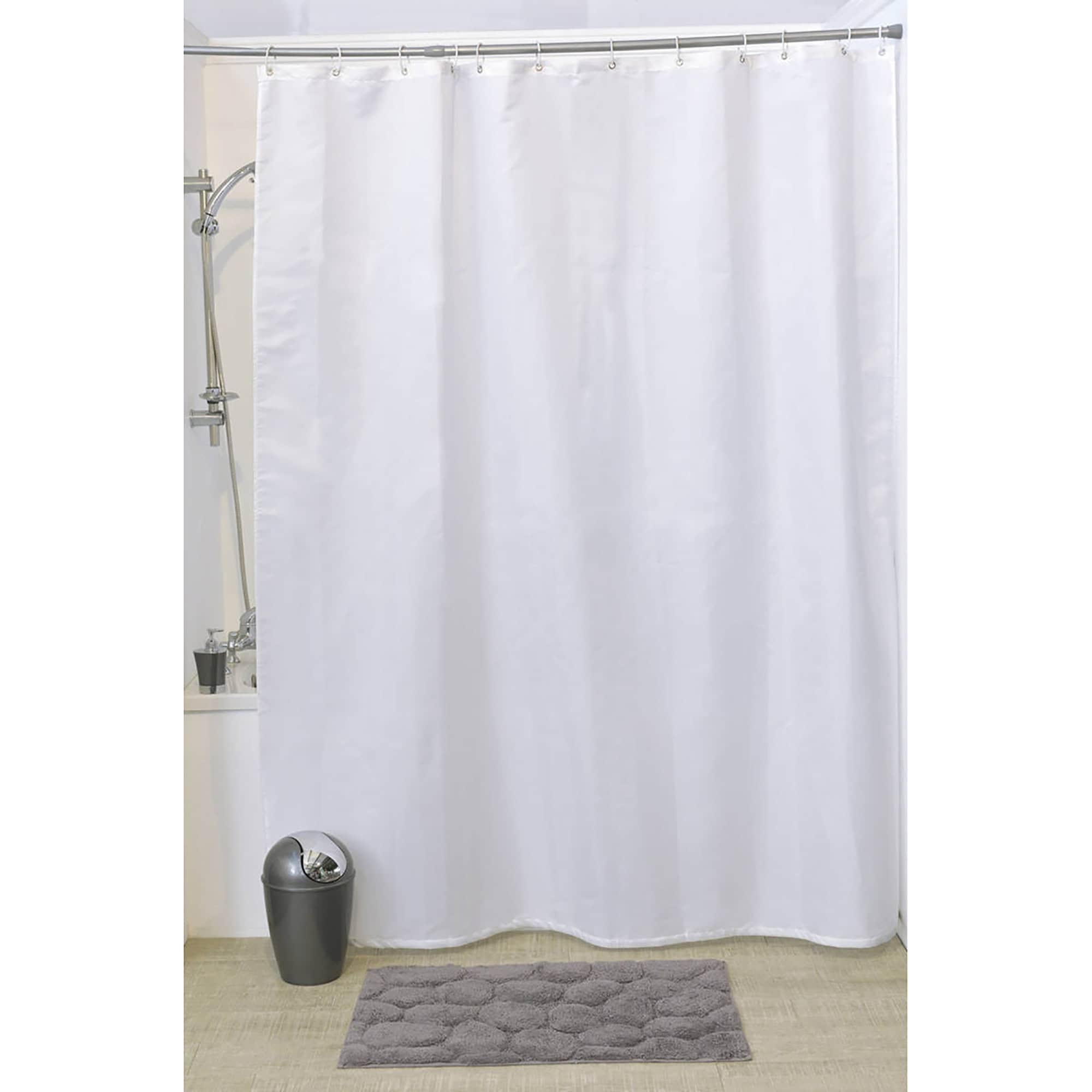White shower curtain hanging in bathroom with grey mat and trash bin