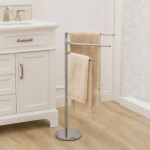 "Chrome 3-swivel-arm towel rack holding beige towels beside white bathroom vanity"