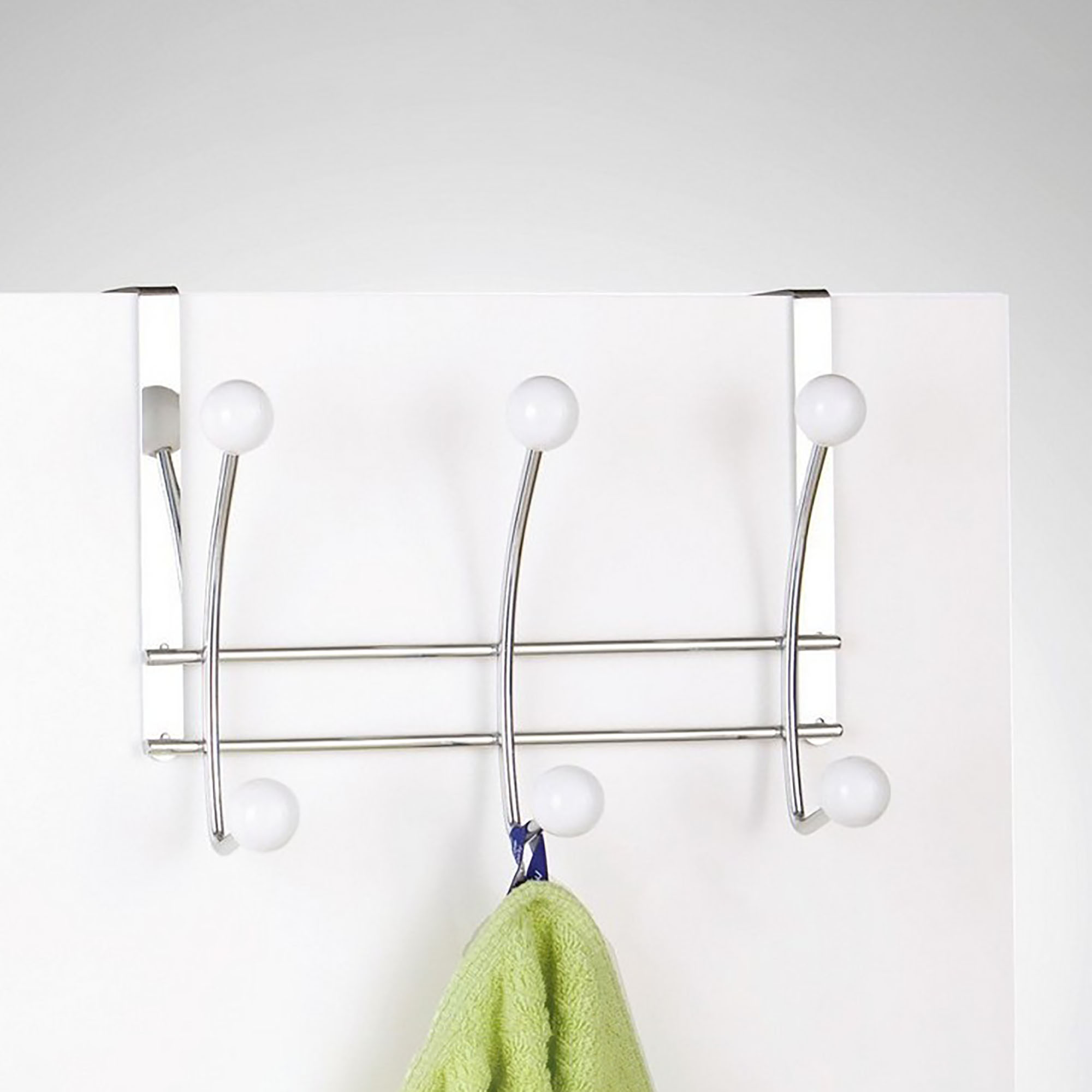 Chrome hook rack hanging on white door holding green towel