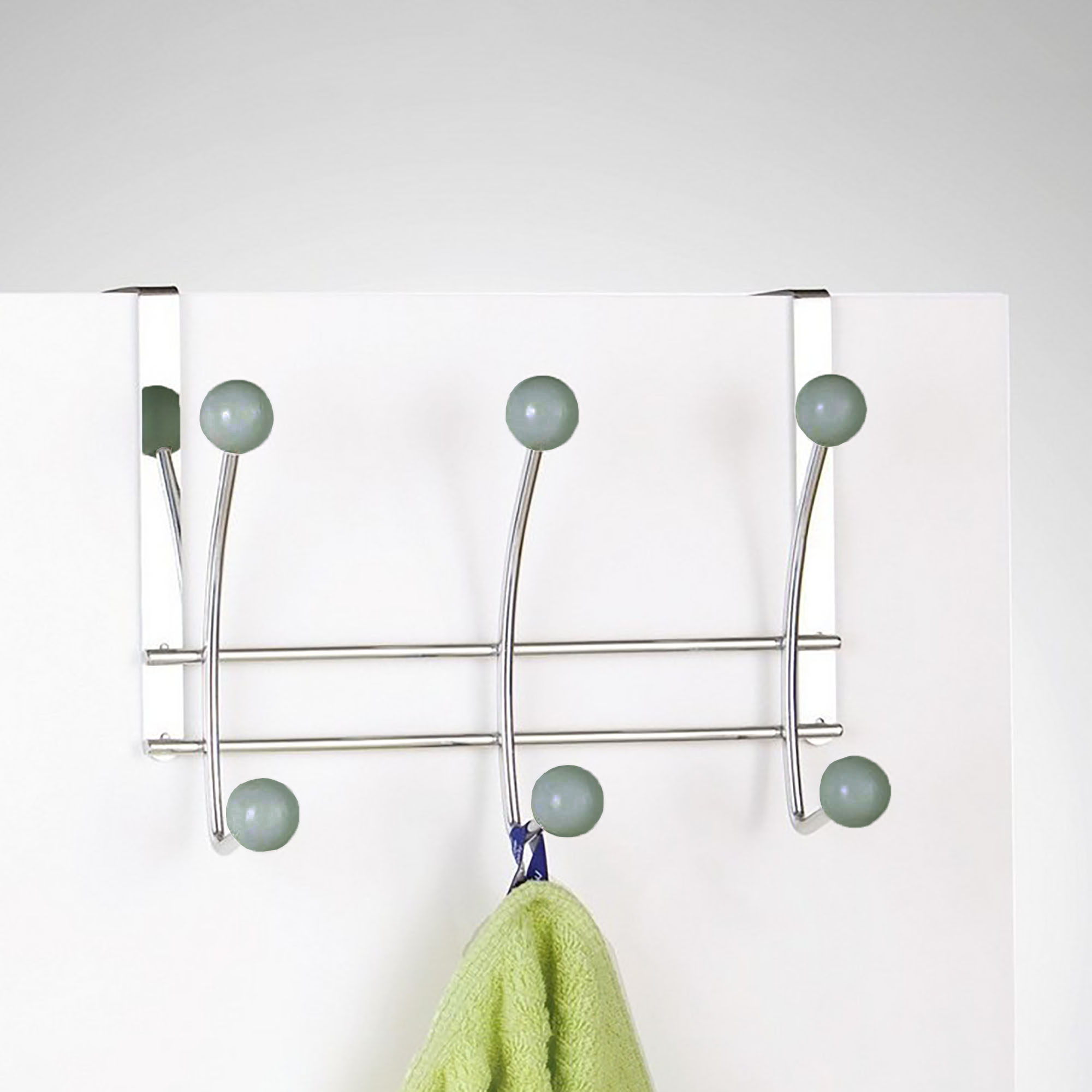 Chrome hook rack hanging on white door holding green towel