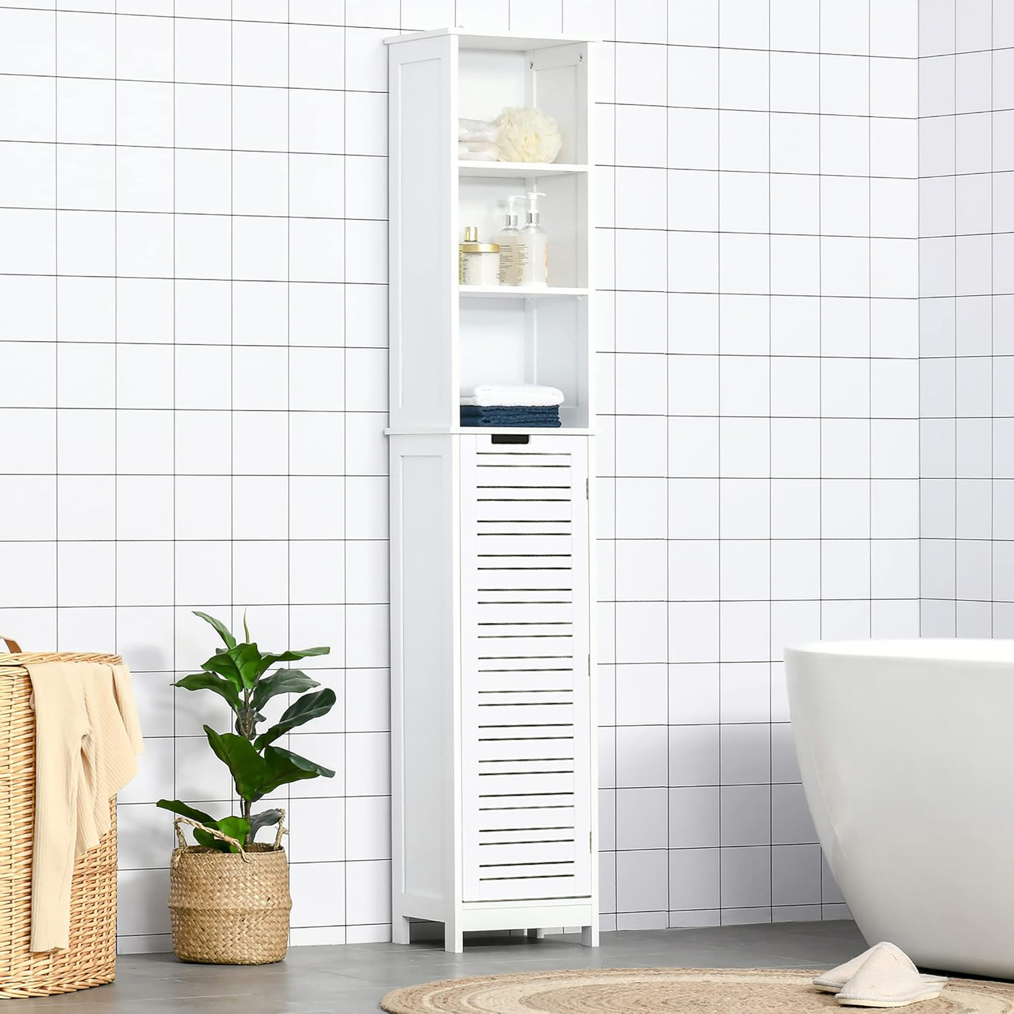 Tall white bathroom storage cabinet staged in a modern bathroom with white tiled walls, decorative plants, and a minimalistic bathtub setup.