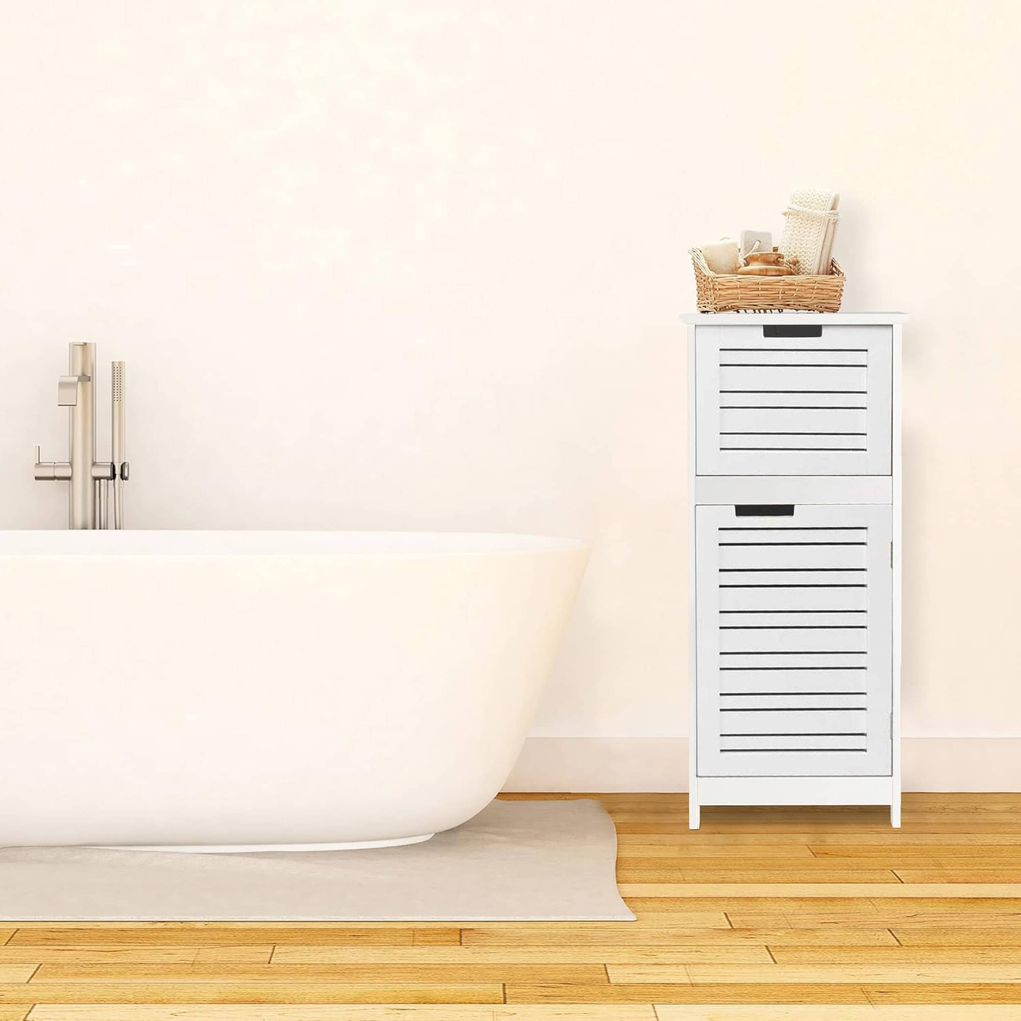 In-use view of compact cabinet by bathtub – White compact storage cabinet placed beside a freestanding bathtub in a minimalist bathroom, styled with a wicker basket holding bathroom accessories.