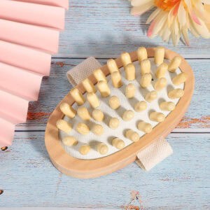 Spa scene with massage brush on weathered wood surface with pink fan and flower