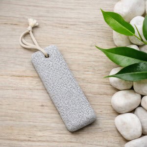 Spa scene with pumice stone, white stones, and plant on light surface