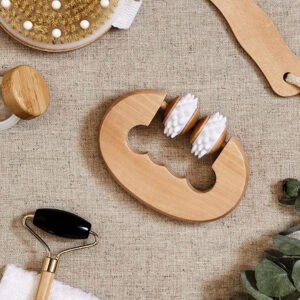 Wooden massage roller styled on linen fabric with spa accessories including jade roller, eucalyptus, and decorative elements
