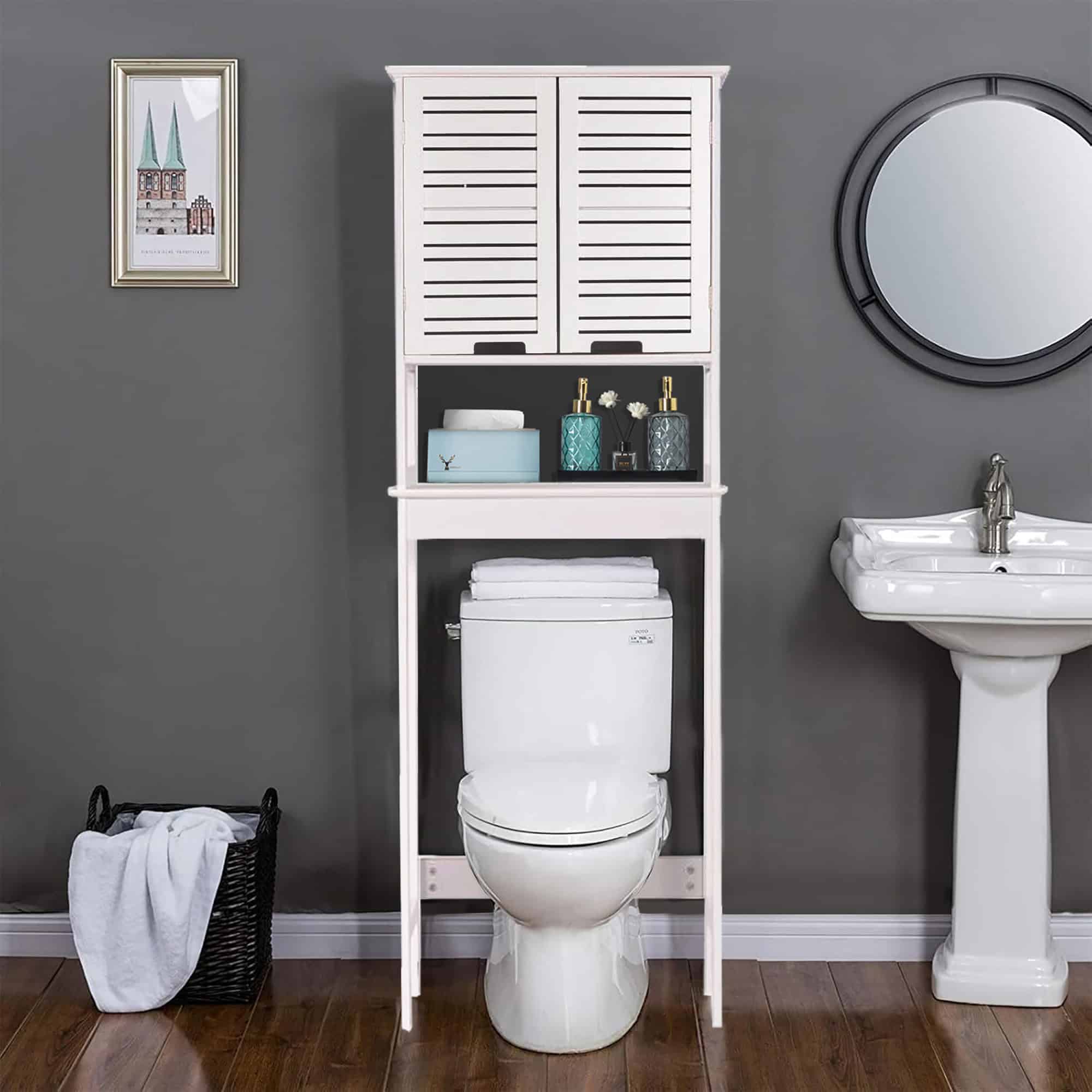 “White over-the-toilet cabinet with slatted doors styled in modern gray bathroom”