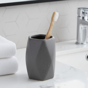 Matte gray stoneware bathroom tumbler with toothbrush on vanity