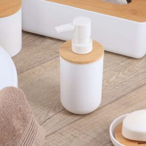 White soap dispenser with bamboo lid on wooden surface