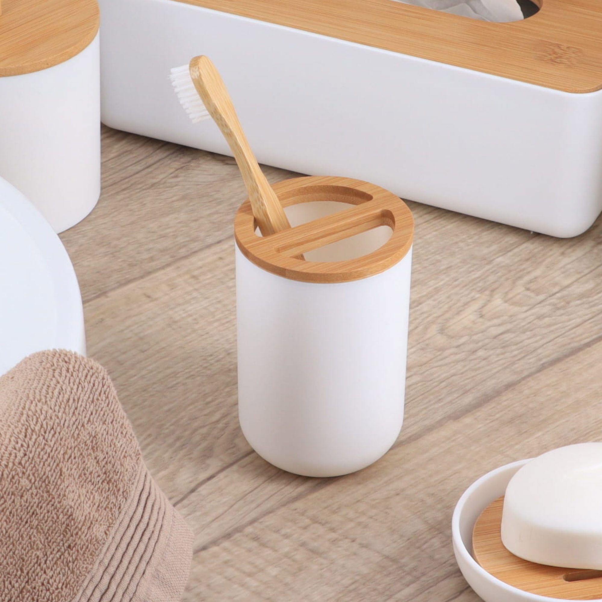 White toothbrush holder with bamboo lid holding toothbrush on wood surface