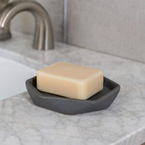 Grey soap dish holding bar soap near sink
