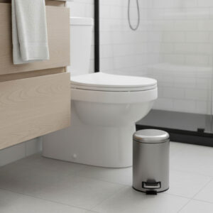 Small round metal bathroom trash can next to toilet with step pedal