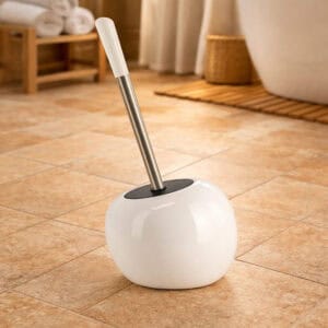White round dolomite toilet brush holder with stainless steel handle in warm bathroom setting