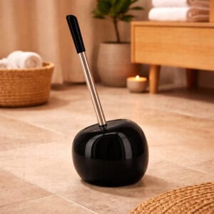 Black round dolomite toilet brush holder with stainless steel handle in warm bathroom setting