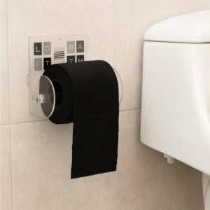 Wall-mounted toilet paper holder with modern letter tile design mounted on beige bathroom wall next to toilet