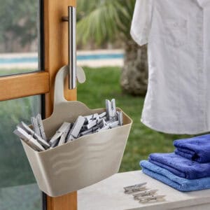 Taupe hanging shower caddy filled with clothespins hanging on outdoor door handle