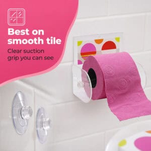 Eclats clear acrylic toilet paper holder on tile holding a pink roll, spare suction cups shown. "Best on smooth tile" / "Clear suction grip you can see".