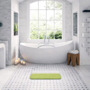 Green and white bi-color bath mat in front of white freestanding bathtub in bright bathroom