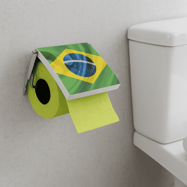 Brazil flag print toilet paper holder screw-mounted on grey wall beside a toilet tank, holding a lime-green roll under a flip-up Brazilian flag cover with paper hanging down.