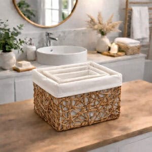 Three natural beige paper rope baskets nested inside the largest basket, displayed empty on a wooden bathroom vanity countertop.