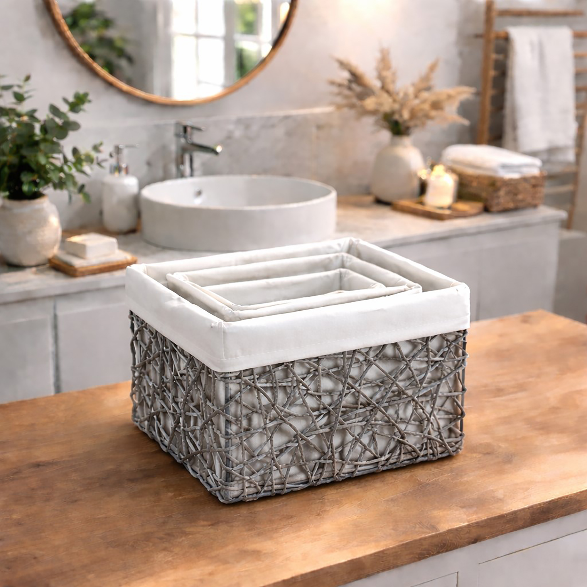 Three gray paper rope baskets nested inside the largest basket, displayed empty on a wooden bathroom vanity countertop.