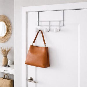 Image 1: Chrome over-the-door hook rack with 3 white ball hooks, holding a tan leather handbag on a white entryway door.