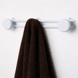 Image 1: White wall-mounted hook rail with 3 round disc hooks, holding a dark brown towel on a white textured wall.