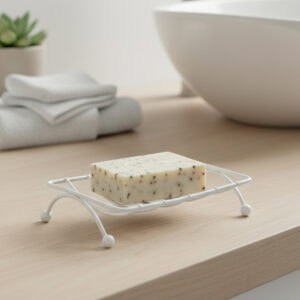 White wire soap holder with speckled bar soap on wooden bathroom counter near white sink
