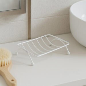 Empty white metal soap dish with curved drainage design on bathroom countertop