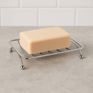 Chrome metal wire soap dish with ball feet holding yellow bar soap on gray counter
