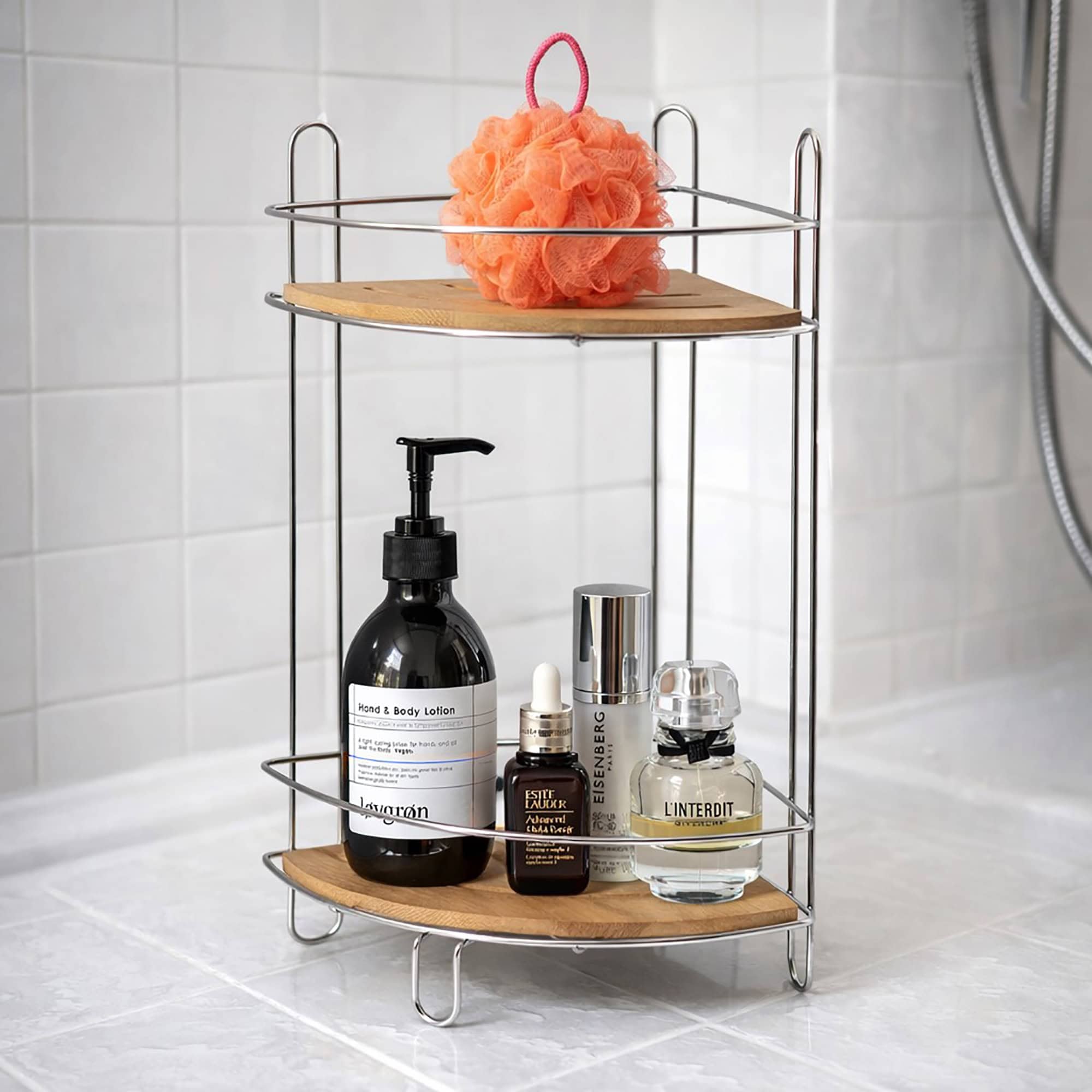 Image 2: Chrome 2-shelf corner storage tower with bamboo shelves holding skincare products and a pink loofah on a white tiled bathroom floor.