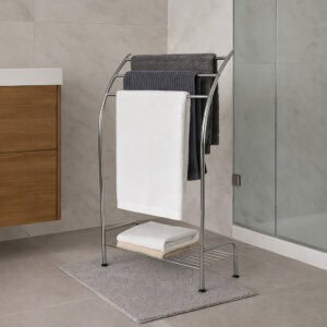 "Chrome 3-bar towel rack holding gray and white towels with folded towels on bottom shelf, next to glass shower"