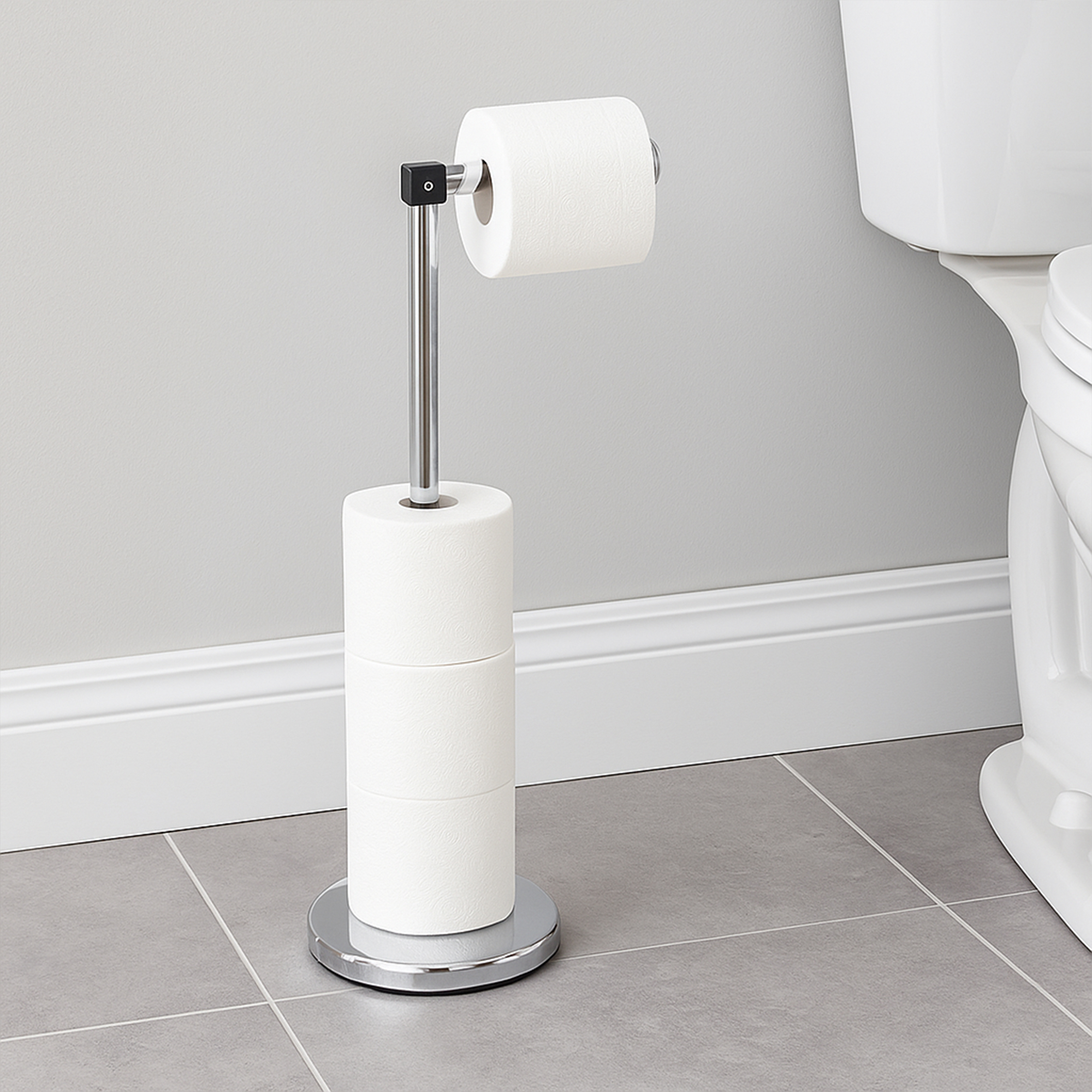 "Chrome freestanding toilet paper holder with 3 reserve rolls next to toilet in gray bathroom"