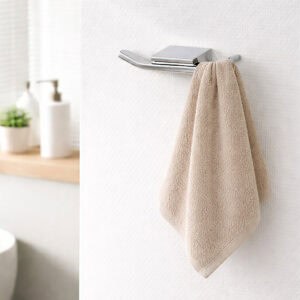"Chrome double wall hook with single beige hand towel draped over left prong"