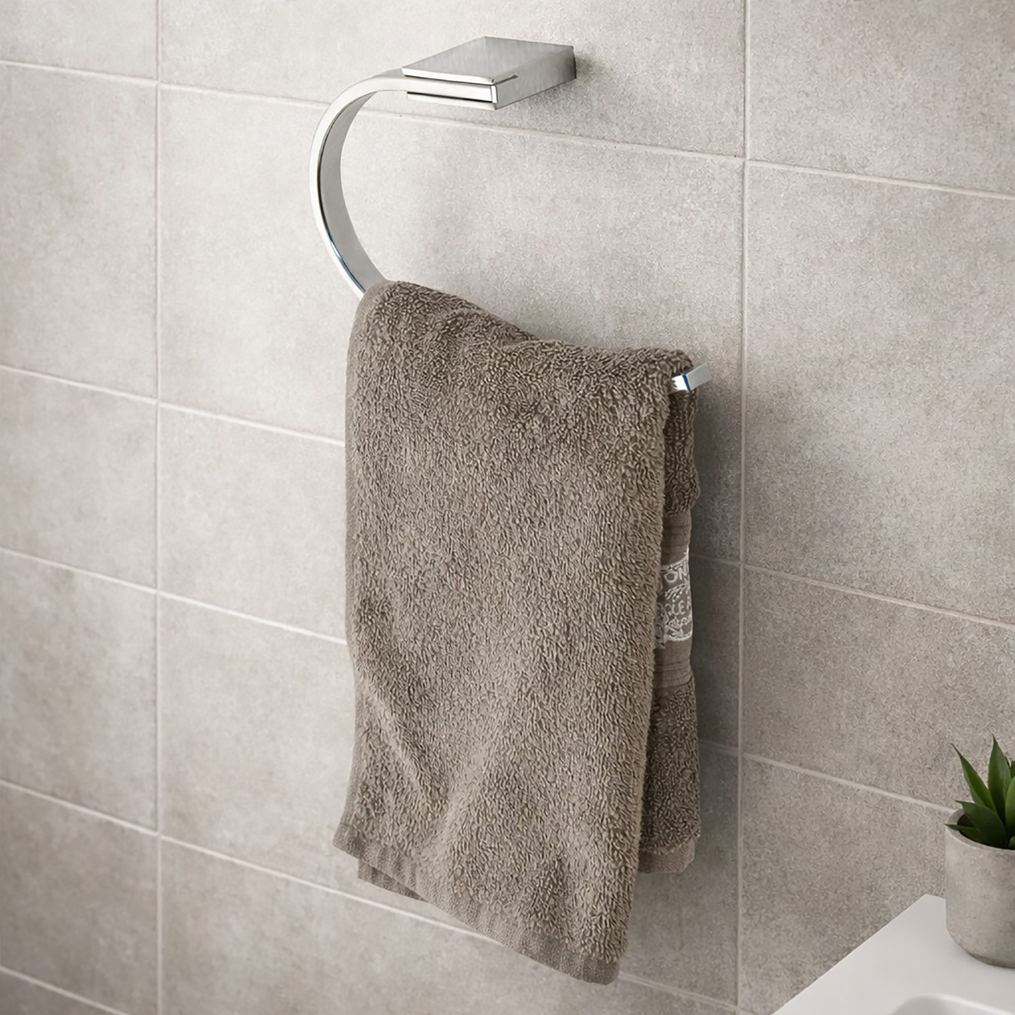 "Chrome towel ring with brown towel mounted on gray tile bathroom wall"
