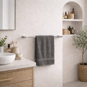 "Chrome towel bar with gray towel in bright neutral bathroom with wood vanity and arched shelving"
